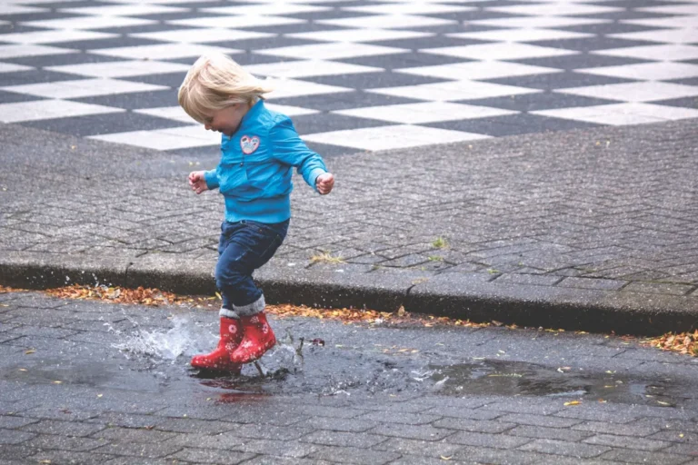 Niño con botas de agua saltando en un charco