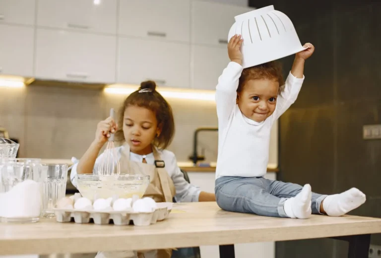 Niño con un colador en la cabeza jugando en la cocina