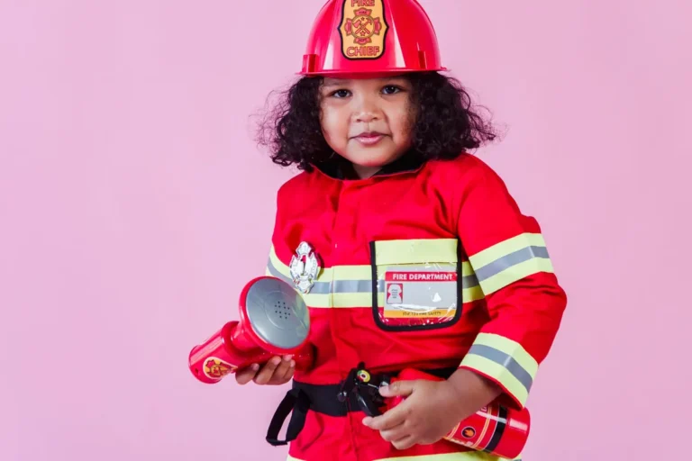 Niños disfrazados de bomberos jugando con un casco y una manguera